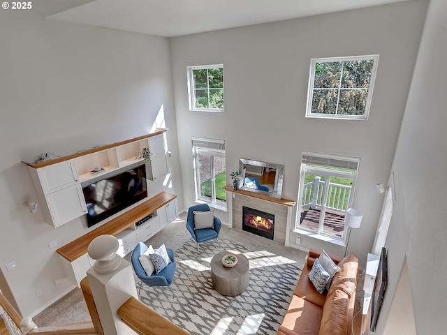 carpeted living area featuring a high ceiling, a tile fireplace, and baseboards
