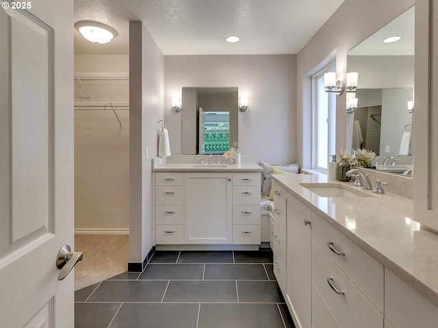full bathroom featuring tile patterned floors, a walk in closet, and two vanities