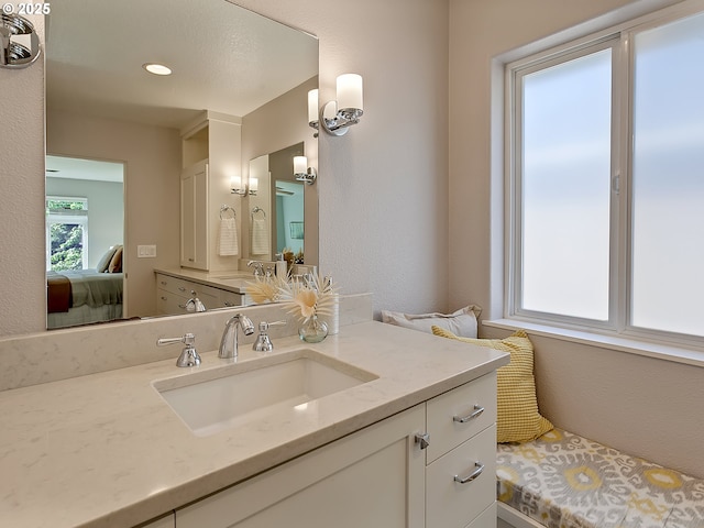 bathroom featuring ensuite bathroom, vanity, and a textured wall