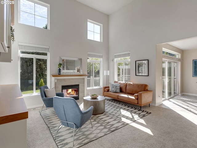 carpeted living area with a tile fireplace, a high ceiling, and baseboards
