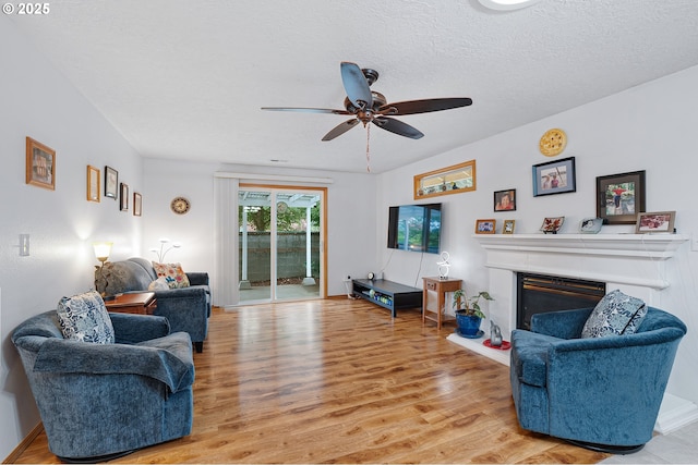 2176 SE 63rd Ave, Hillsboro, OR 97123 - living area with light wood-style flooring, ceiling fan, a glass covered fireplace, and a textured ceiling