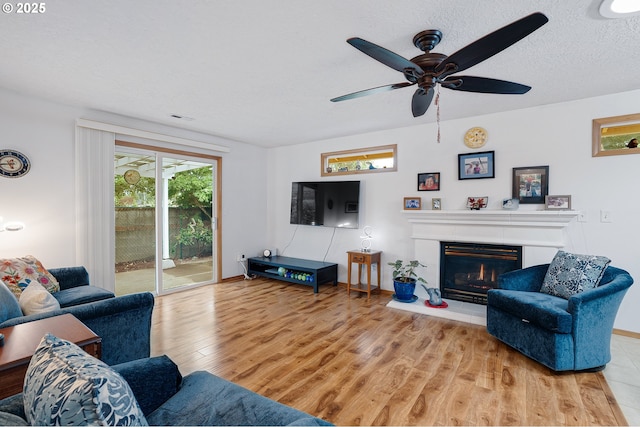 2176 SE 63rd Ave, Hillsboro, OR 97123 - living room with wood finished floors, a ceiling fan, a glass covered fireplace, and a textured ceiling