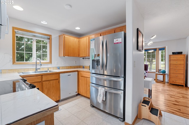 2176 SE 63rd Ave, Hillsboro, OR 97123 - kitchen featuring stainless steel refrigerator with ice dispenser, dishwasher, a sink, light tile patterned flooring, and plenty of natural light