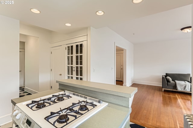 2566 NW Lovejoy St Unit 4, Portland, OR 97210 - kitchen featuring baseboards, white range with gas stovetop, wood-type flooring, recessed lighting, and light countertops
