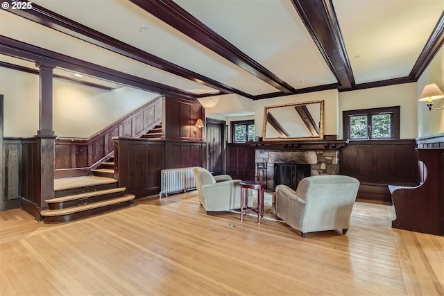2566 NW Lovejoy St Unit 4, Portland, OR 97210 - living room with radiator heating unit, wainscoting, a fireplace, light wood-style flooring, and crown molding