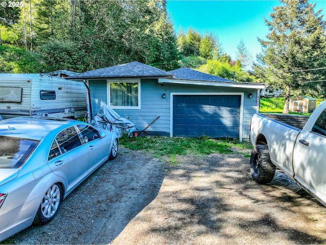 view of side of property with roof with shingles, driveway, and an attached garage