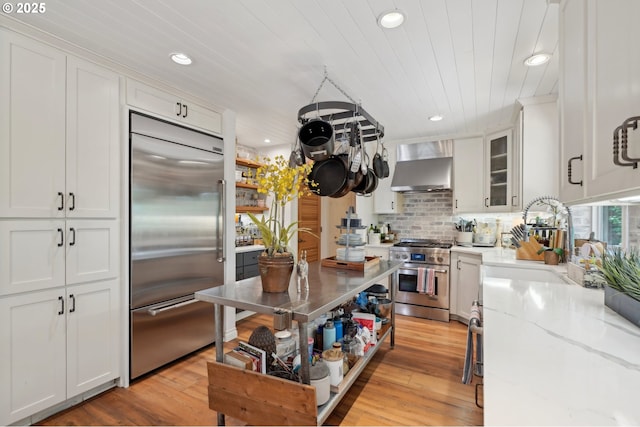 15785 SW Bull Mountain Rd, Portland, OR 97224 - kitchen featuring high end appliances, wall chimney exhaust hood, white cabinets, recessed lighting, and light stone countertops