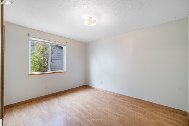 spare room featuring wood finished floors, baseboards, and a textured ceiling