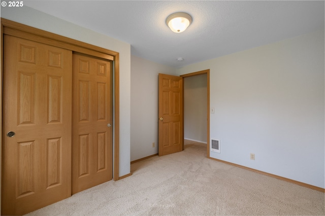 unfurnished bedroom featuring light carpet, baseboards, and a closet