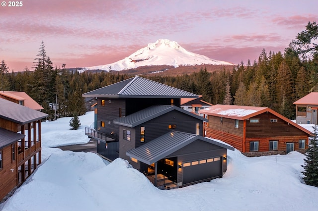 exterior space featuring a wooded view, a standing seam roof, a garage, a mountain view, and metal roof