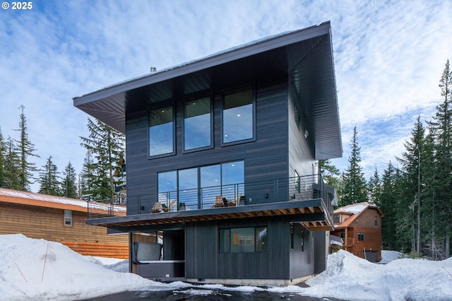 snow covered back of property with a balcony