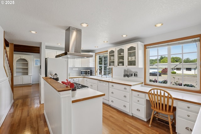 243 N 30th Ct, Cornelius, OR 97113 - kitchen with white appliances, island exhaust hood, light wood finished floors, glass insert cabinets, and white cabinetry
