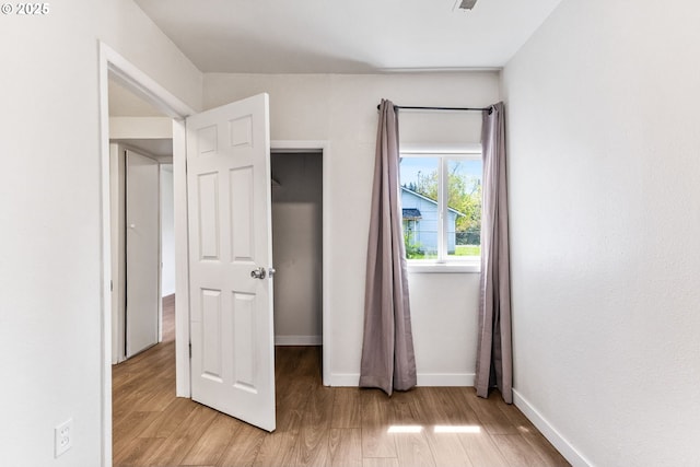 unfurnished bedroom featuring light wood-style floors, baseboards, and visible vents
