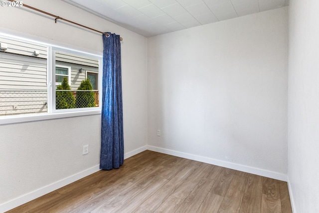 spare room with baseboards and wood finished floors