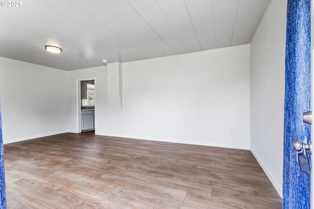 spare room featuring baseboards and wood finished floors
