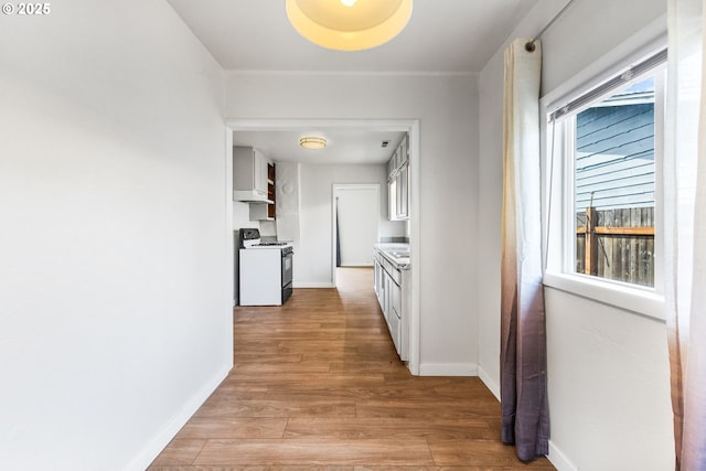 corridor with baseboards and light wood-style flooring
