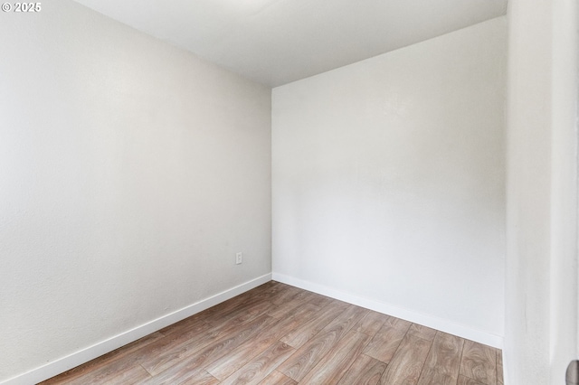 unfurnished room with baseboards and light wood-type flooring