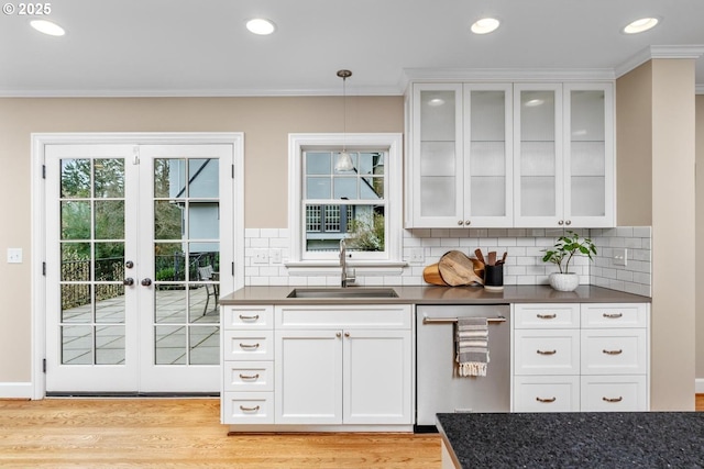 kitchen featuring a sink, backsplash, dark countertops, white cabinetry, and light wood finished floors