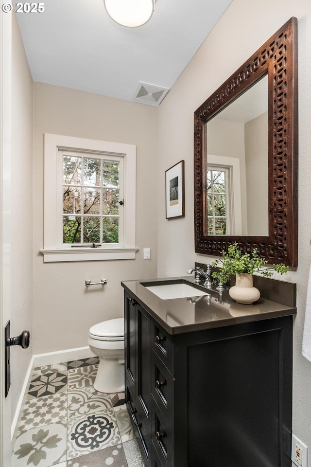 half bathroom featuring tile patterned flooring, visible vents, baseboards, toilet, and vanity