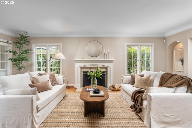 living room with a healthy amount of sunlight, ornamental molding, and a fireplace