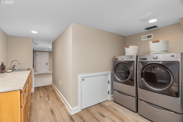 washroom featuring visible vents, separate washer and dryer, light wood-style flooring, and a sink