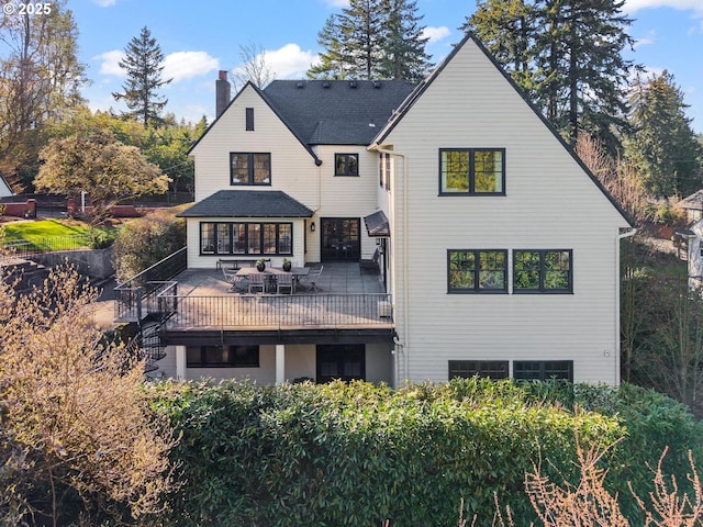 back of house with a wooden deck and a chimney