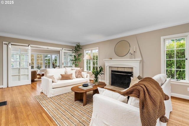 living area featuring light wood-type flooring, baseboards, visible vents, and a fireplace