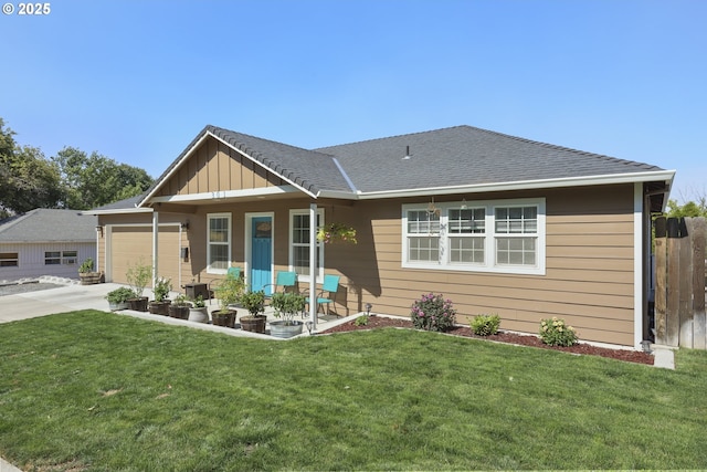 view of front facade with roof with shingles, a front yard, fence, a garage, and driveway