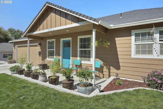 entrance to property featuring board and batten siding, a garage, a yard, and a shingled roof