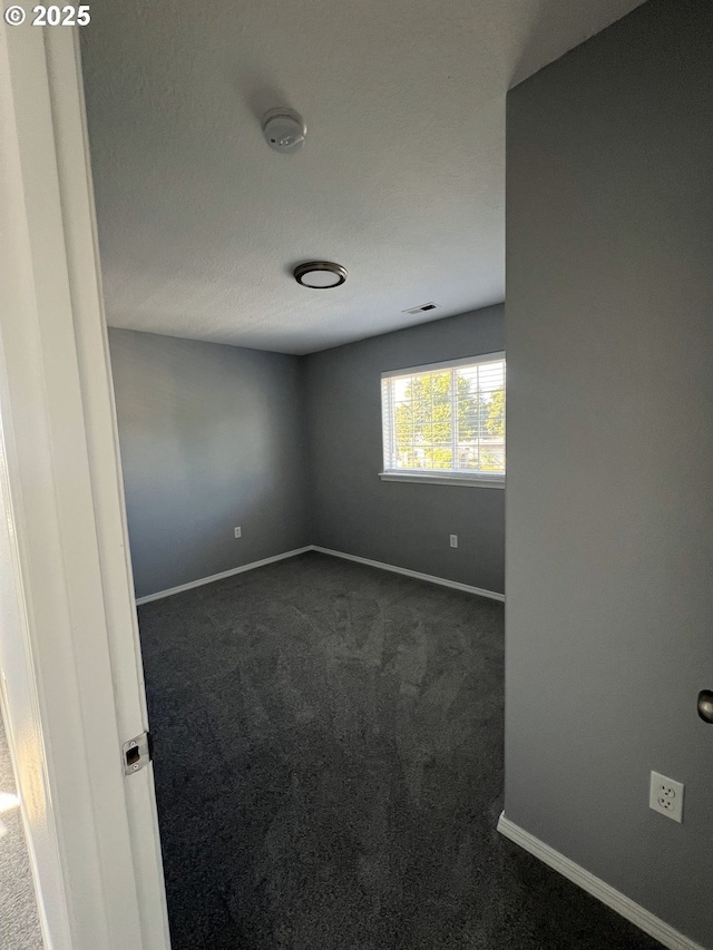 unfurnished room featuring dark carpet