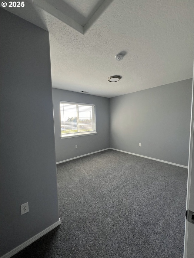 carpeted empty room featuring a textured ceiling