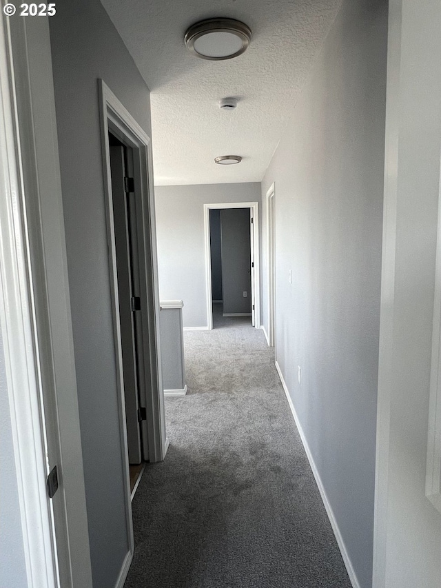 hallway with light colored carpet and a textured ceiling