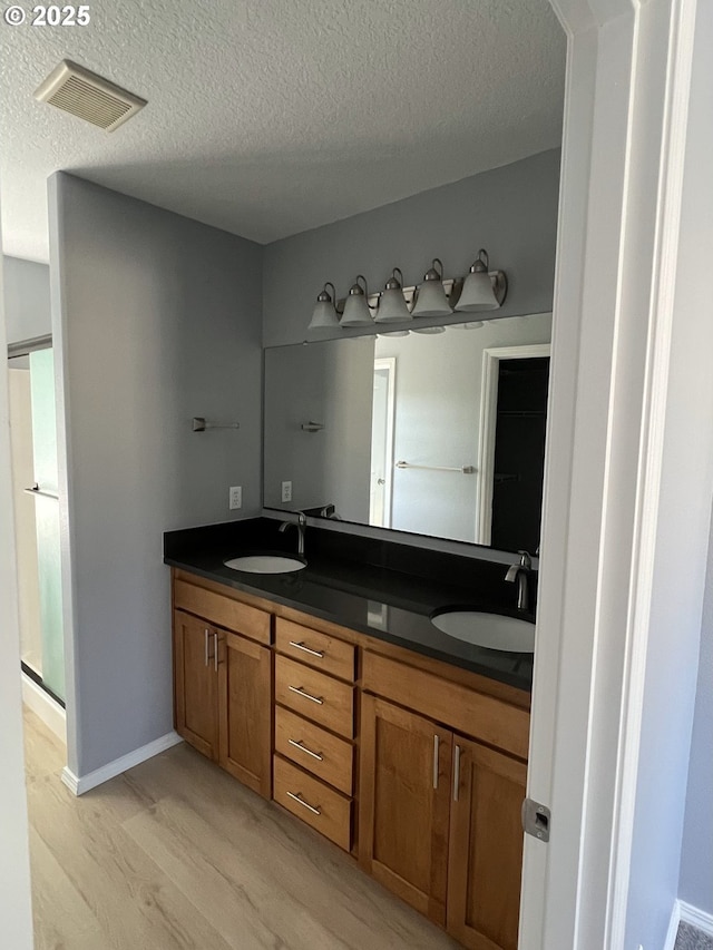 bathroom featuring hardwood / wood-style flooring, vanity, and a textured ceiling