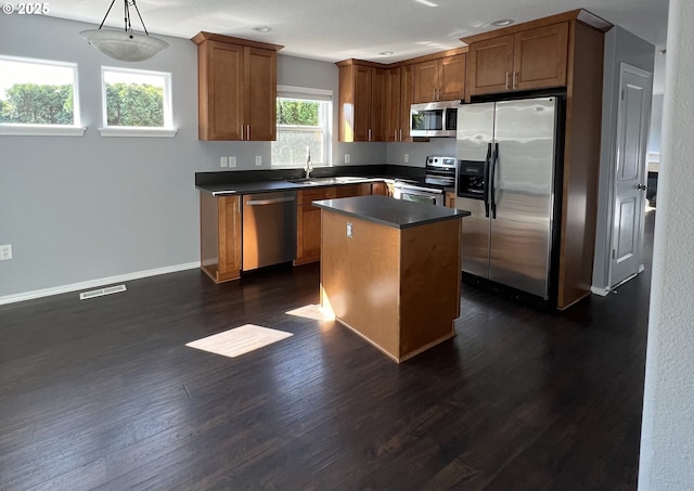 kitchen featuring sink, hanging light fixtures, stainless steel appliances, a kitchen island, and dark hardwood / wood-style flooring