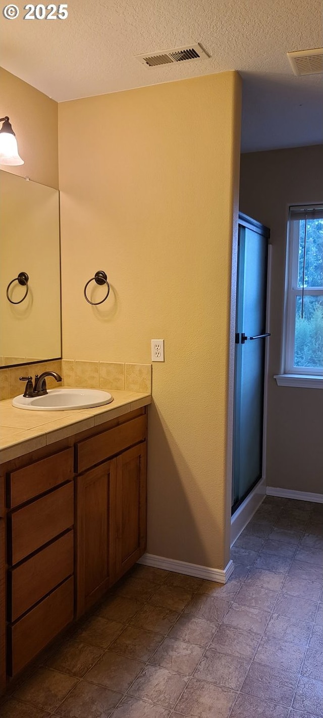 bathroom featuring vanity, an enclosed shower, and a textured ceiling