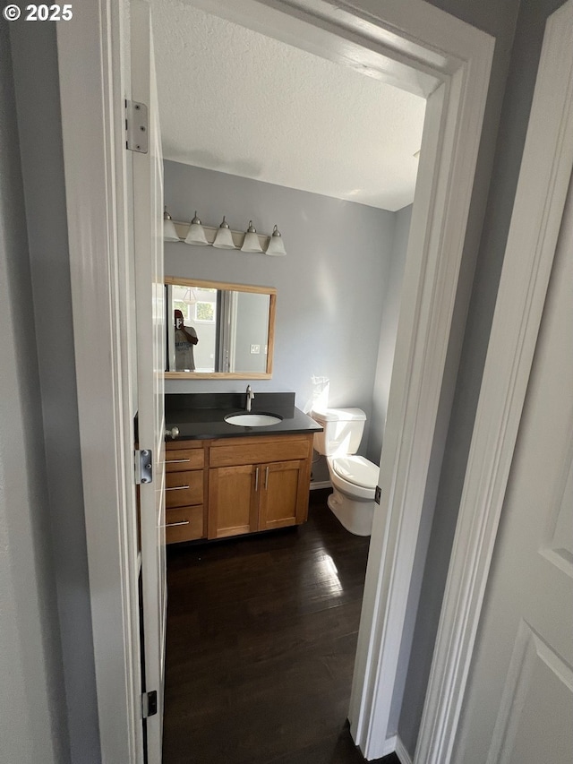 bathroom featuring vanity, hardwood / wood-style floors, a textured ceiling, and toilet