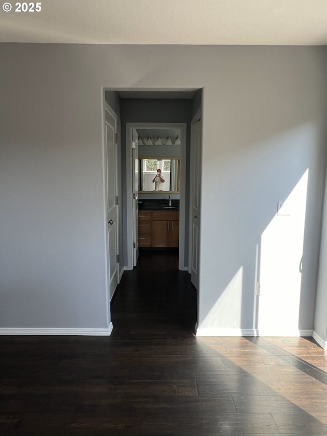 corridor with dark wood-type flooring and sink