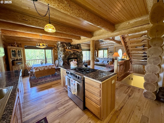 44552 Red Boy Rd, Granite, OR 97877 - kitchen featuring stainless steel gas range oven, rustic walls, light wood finished floors, a wooden ceiling with exposed beams, and a stone fireplace