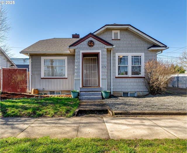 bungalow-style house featuring entry steps, roof with shingles, a chimney, and fence