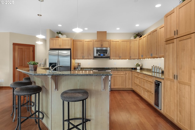 123 S Hemlock St # 201, Cannon Beach, OR 97110 - kitchen featuring stainless steel appliances, light brown cabinetry, wine cooler, wood finished floors, and dark stone counters
