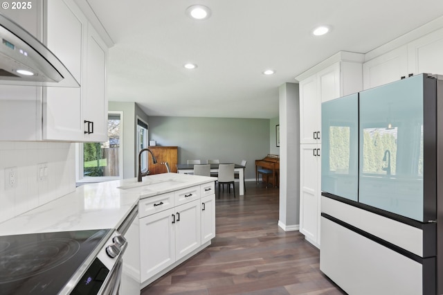 kitchen with light stone counters, stainless steel appliances, a sink, white cabinets, and under cabinet range hood