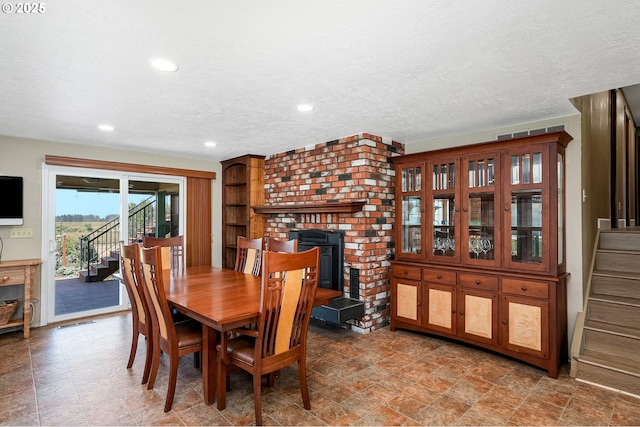 41266 Manitau Rd SE, Stayton, OR 97383 - dining room featuring stairs, a brick fireplace, a textured ceiling, and recessed lighting