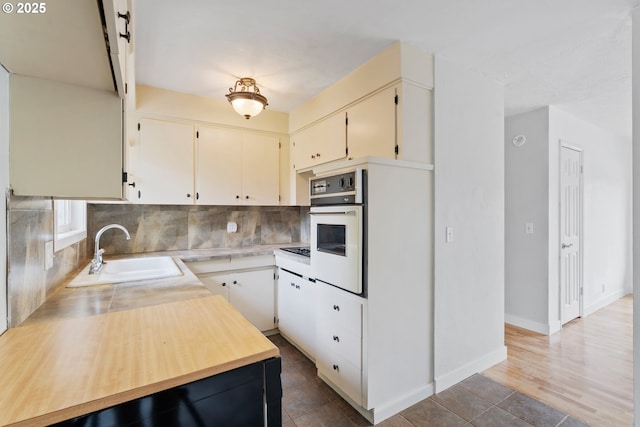 2222 34th Ave, Albany, OR 97322 - kitchen featuring a sink, white oven, decorative backsplash, black electric stovetop, and baseboards