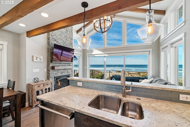 kitchen with light stone counters, open floor plan, a sink, and decorative light fixtures