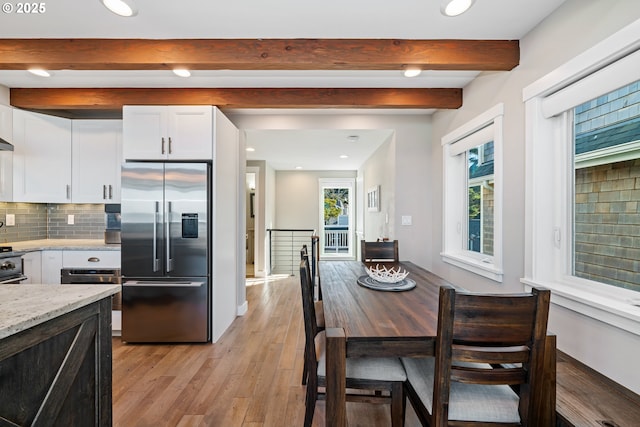 kitchen with high end fridge, backsplash, light stone countertops, and white cabinets