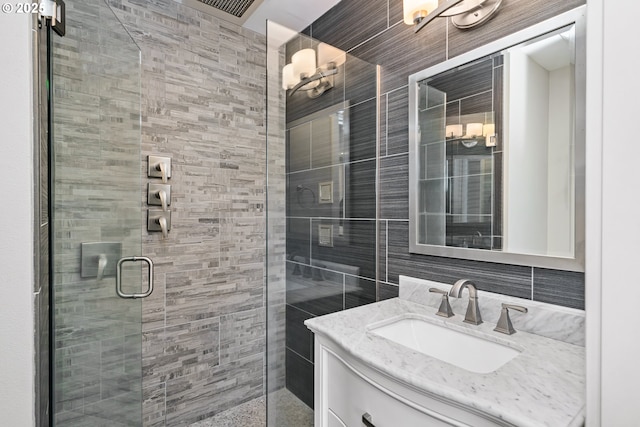 bathroom featuring a shower stall, vanity, and tile walls