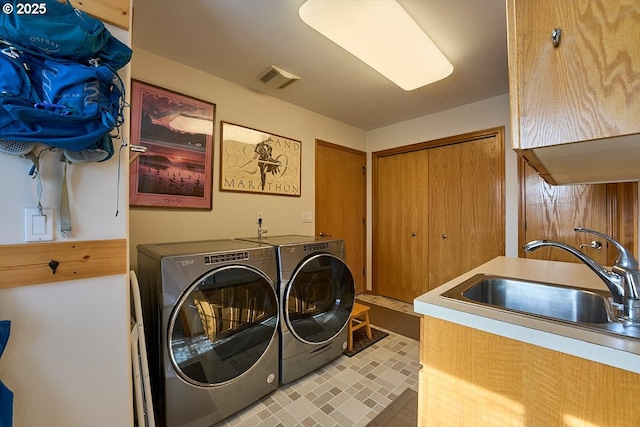 clothes washing area with a sink, separate washer and dryer, and visible vents