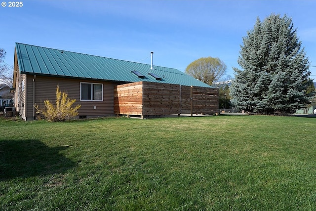 rear view of house featuring a lawn, a standing seam roof, and metal roof