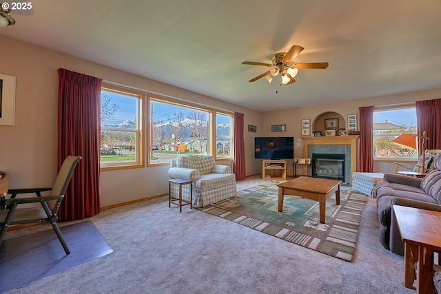 carpeted living room featuring a tiled fireplace, baseboards, and ceiling fan