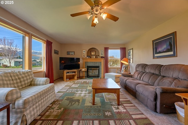 carpeted living room with plenty of natural light, a ceiling fan, and a tile fireplace